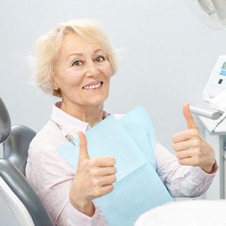 Senior woman in dental chair giving two thumbs up
