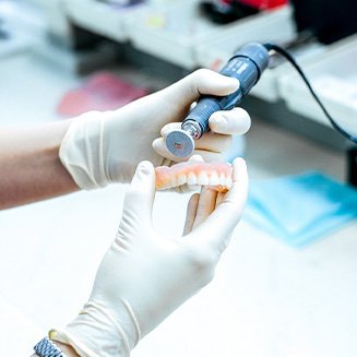 Dental lab technician making adjustments to dentures