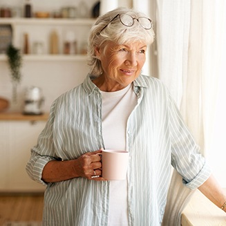 Woman having cup of coffee while looking out window