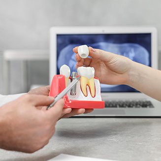 Dentist showing patient model of dental implant