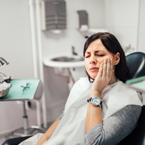 Woman with toothache sitting in treatment chair