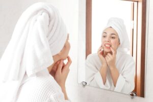 Woman in front of bathroom mirror, inspecting her teeth
