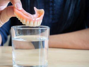 Person putting their dentures in water for the night